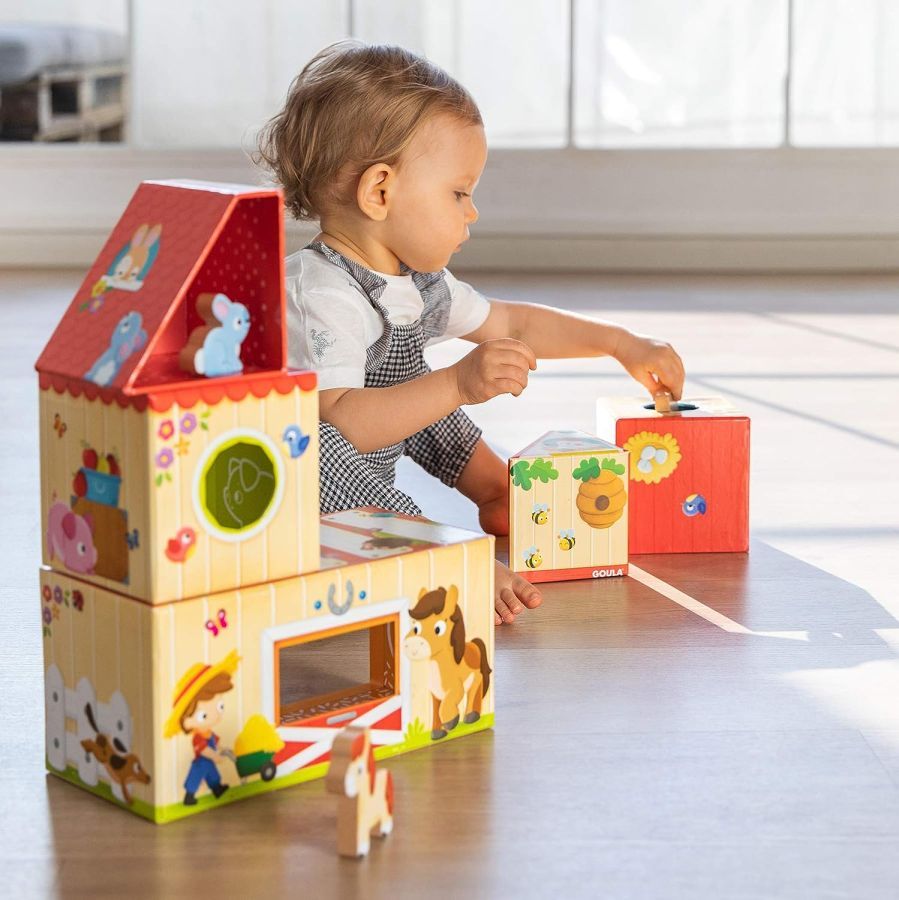 Niño jugando con una casa de madera de la marca Goula.